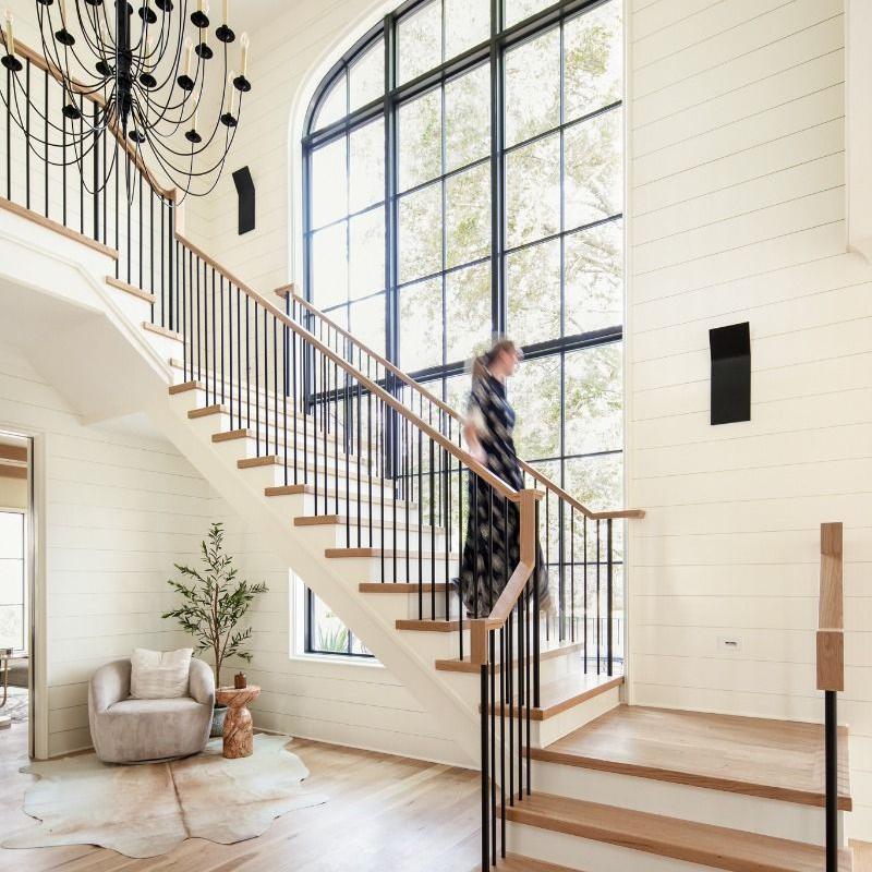 A woman is walking down the wooden staircase.